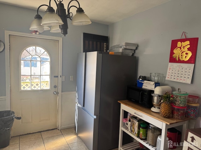 kitchen featuring freestanding refrigerator, black microwave, and light tile patterned floors
