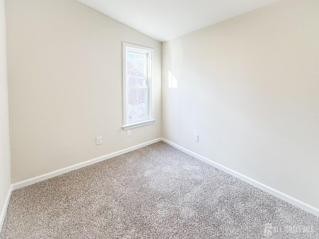 carpeted empty room featuring vaulted ceiling