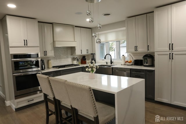 kitchen featuring white cabinetry, stainless steel appliances, a center island, and pendant lighting