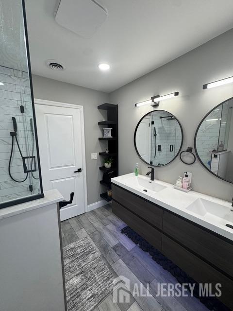 bathroom featuring vanity, a tile shower, and hardwood / wood-style floors