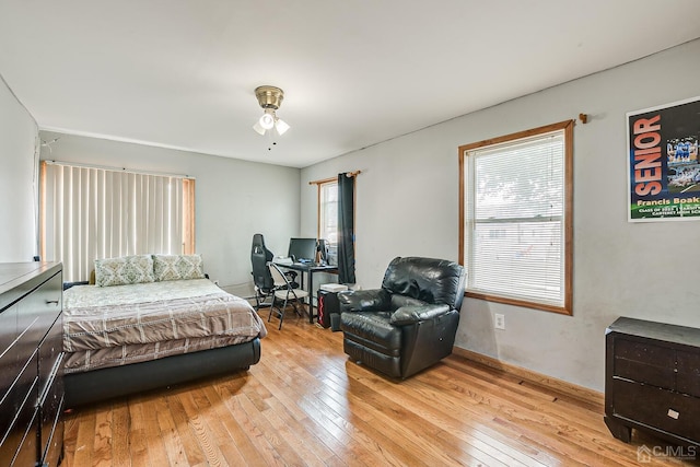 bedroom with multiple windows, light hardwood / wood-style flooring, and ceiling fan