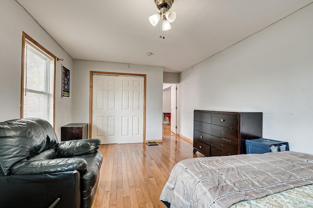 bedroom featuring baseboards, a closet, light wood finished floors, and ceiling fan