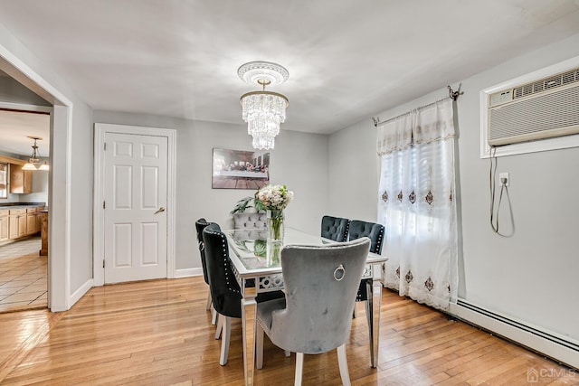 dining room featuring a baseboard heating unit, a notable chandelier, a wall mounted AC, and light wood-type flooring