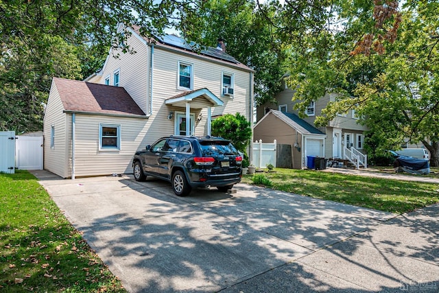 traditional style home featuring a front lawn, a gate, fence, roof with shingles, and solar panels