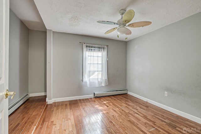 spare room featuring a baseboard heating unit, baseboards, and hardwood / wood-style floors