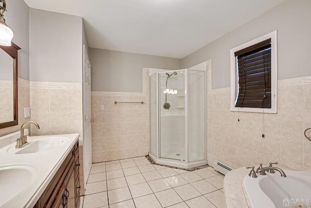 bathroom with a baseboard heating unit, tile walls, a shower stall, and a sink