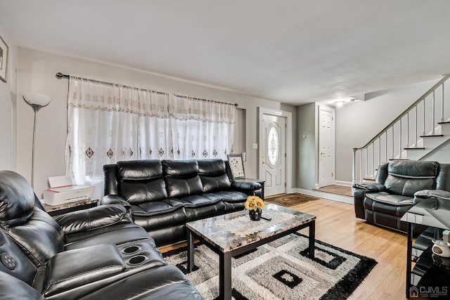 living area with stairway, baseboards, and light wood-style floors