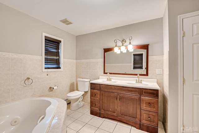 bathroom featuring tile patterned floors, toilet, tile walls, vanity, and tiled bath