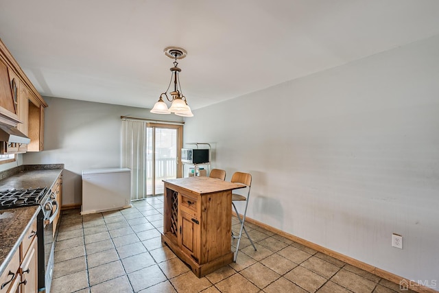 kitchen featuring pendant lighting, refrigerator, a breakfast bar area, a notable chandelier, and stainless steel range with gas stovetop