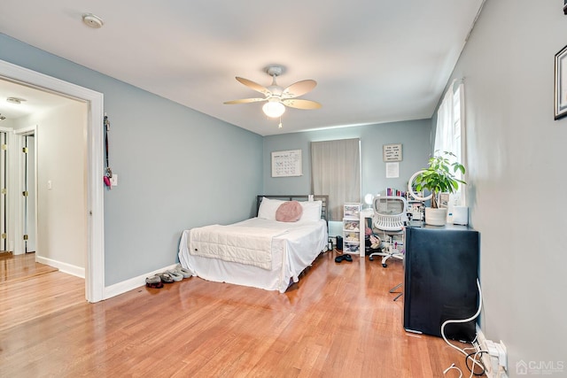 bedroom featuring a ceiling fan, baseboards, and light wood finished floors