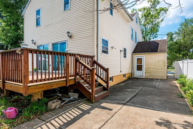 back of house with a deck, a patio area, fence, and a shingled roof