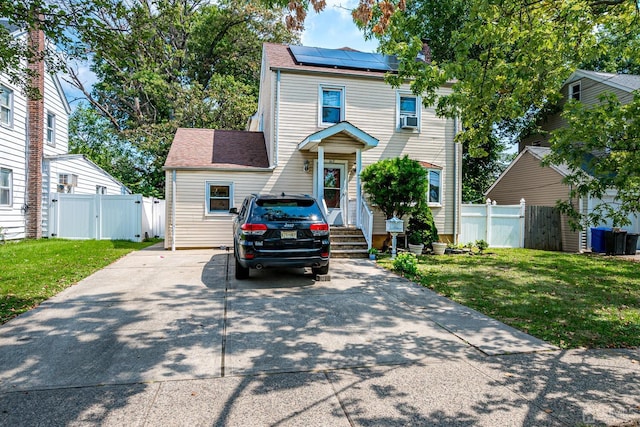 view of front facade featuring roof mounted solar panels, fence, a front yard, and a gate