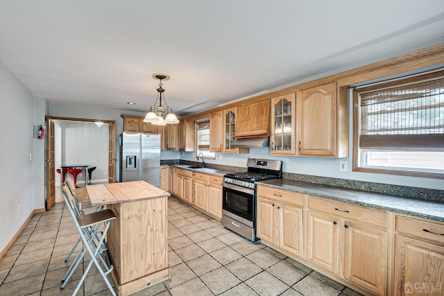 kitchen featuring glass insert cabinets, a breakfast bar, light tile patterned floors, stainless steel appliances, and a sink