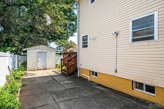 view of side of home with an outbuilding, a storage shed, a patio, and fence