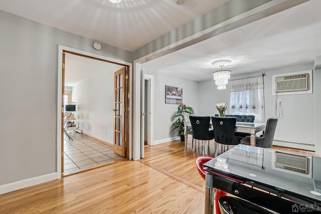 dining space with a wall mounted air conditioner, a baseboard heating unit, wood finished floors, an inviting chandelier, and baseboards