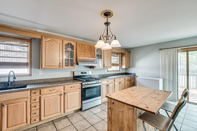 kitchen featuring a breakfast bar, sink, stainless steel gas stove, an inviting chandelier, and a center island