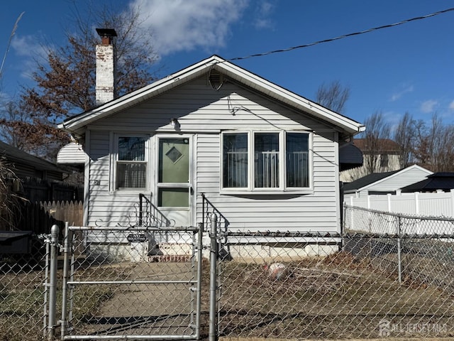 bungalow-style home featuring entry steps, a fenced front yard, a gate, and a chimney