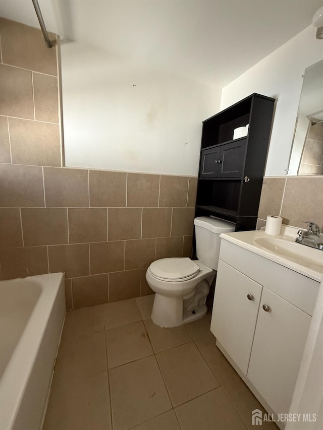 full bathroom featuring wainscoting, toilet, tile patterned flooring, vanity, and tile walls