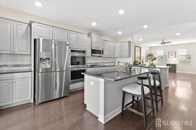905 Chalmers Ln, Monroe, NJ 08831 - kitchen with appliances with stainless steel finishes, a kitchen breakfast bar, dark wood-type flooring, a center island, and recessed lighting