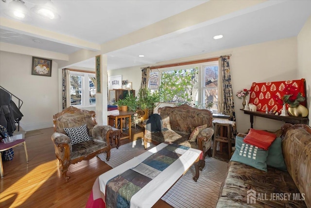 living room with a healthy amount of sunlight, hardwood / wood-style floors, and beamed ceiling