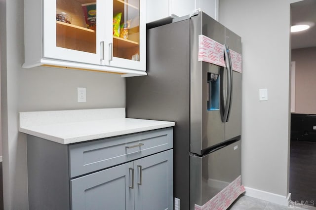 kitchen featuring gray cabinetry, light tile patterned floors, and stainless steel refrigerator with ice dispenser