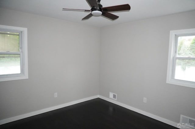 empty room with a wealth of natural light, ceiling fan, and hardwood / wood-style flooring