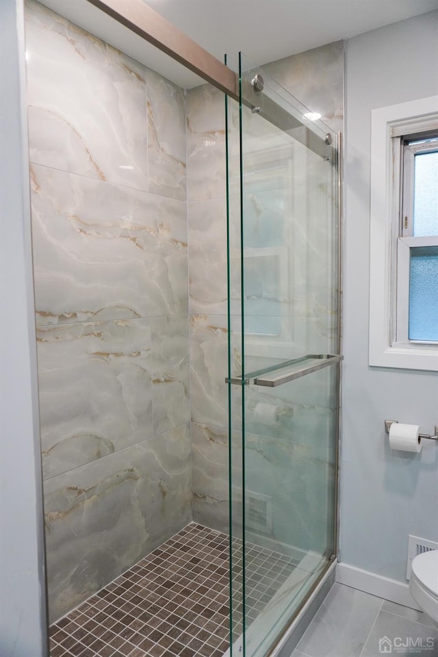 bathroom with tile patterned flooring, toilet, and an enclosed shower