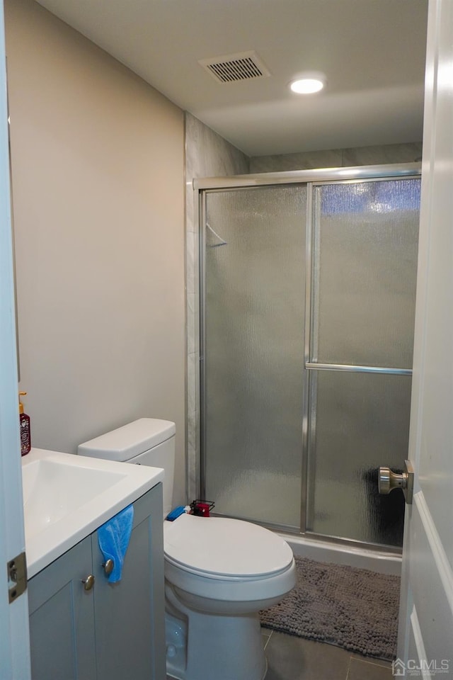 bathroom featuring tile patterned flooring, vanity, toilet, and an enclosed shower