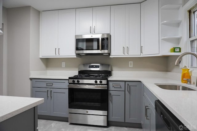 kitchen featuring gray cabinetry, white cabinets, sink, light stone counters, and stainless steel appliances