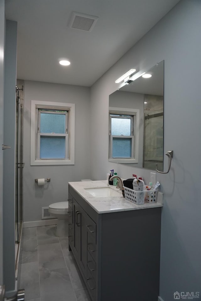 bathroom featuring vanity, toilet, and a shower with shower door