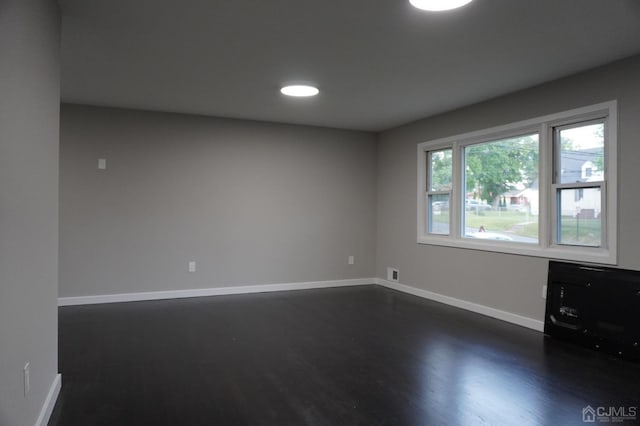 unfurnished room with dark wood-type flooring