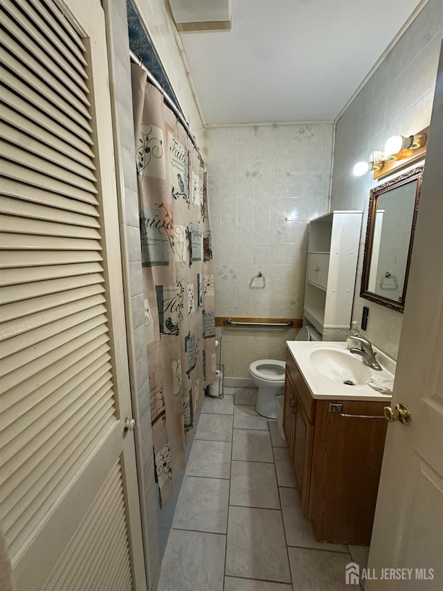 bathroom with tile patterned floors, toilet, a shower with shower curtain, tile walls, and vanity