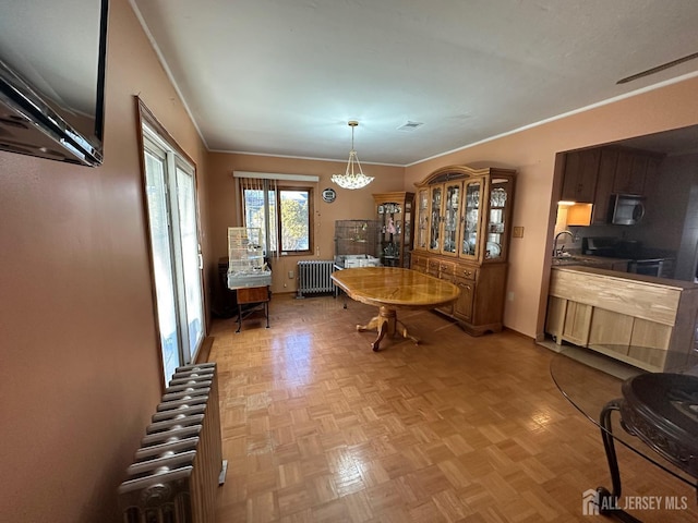 dining area featuring ornamental molding, radiator heating unit, visible vents, and a chandelier