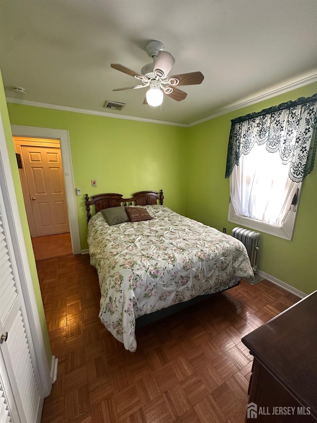 bedroom with visible vents, crown molding, ceiling fan, baseboards, and radiator heating unit