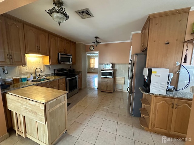 kitchen with visible vents, a sink, appliances with stainless steel finishes, light tile patterned flooring, and crown molding