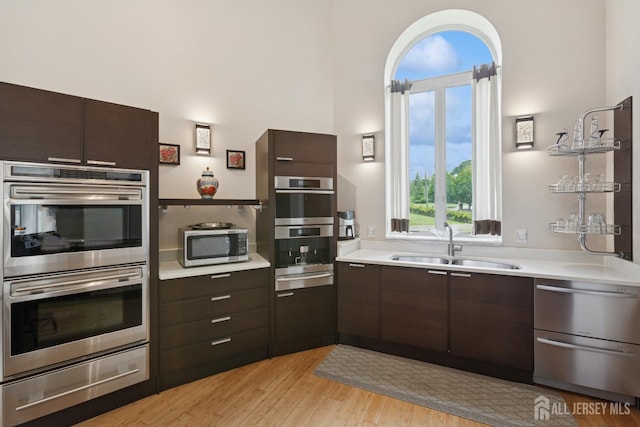 27 Mare Haven Ct, North Brunswick, NJ 08902 - kitchen with appliances with stainless steel finishes, a warming drawer, light countertops, dark brown cabinets, and light wood-style floors