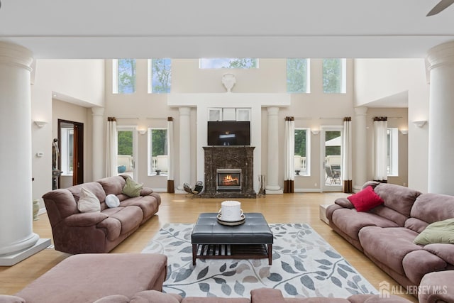 27 Mare Haven Ct, North Brunswick, NJ 08902 - living area featuring ornate columns, a towering ceiling, a fireplace, and light wood-type flooring