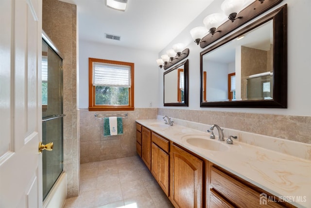 53 Rath Ln, East Brunswick, NJ 08816 - bathroom with tile walls, tile patterned floors, double vanity, wainscoting, and combined bath / shower with glass door