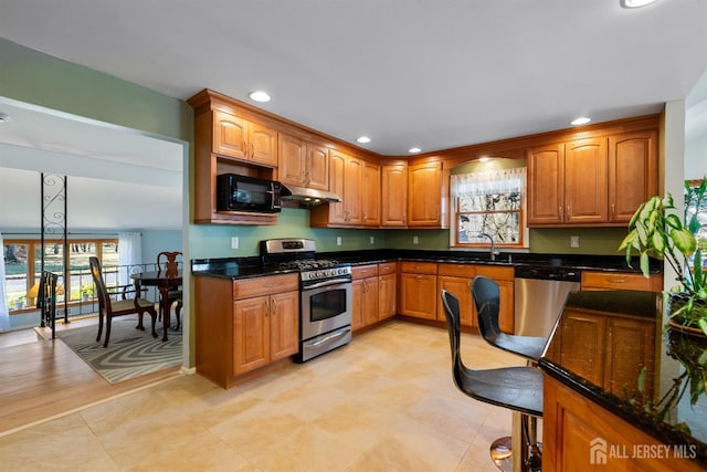 53 Rath Ln, East Brunswick, NJ 08816 - kitchen featuring appliances with stainless steel finishes, under cabinet range hood, recessed lighting, dark stone countertops, and brown cabinetry