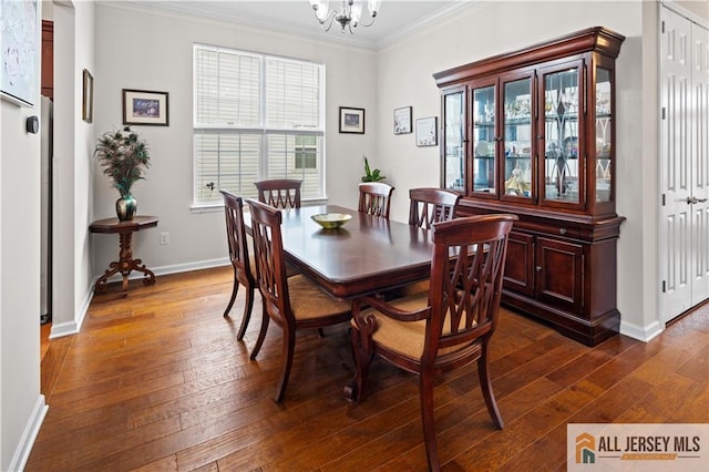 dining room featuring dark wood-style floors, baseboards, an inviting chandelier, and ornamental molding