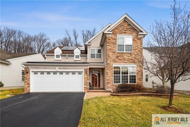 traditional home with driveway, stone siding, roof mounted solar panels, an attached garage, and a front yard