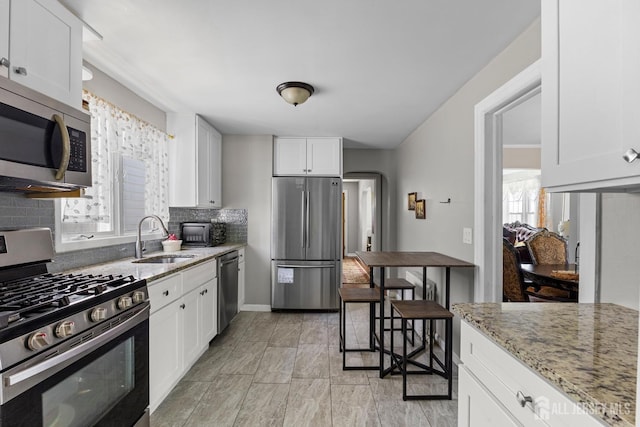 kitchen featuring backsplash, white cabinetry, appliances with stainless steel finishes, and a sink