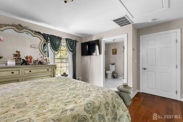 bedroom featuring attic access, visible vents, dark wood finished floors, baseboards, and connected bathroom