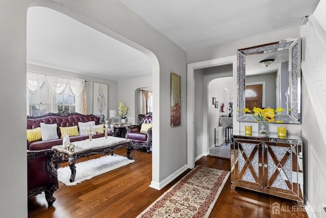 hallway with baseboards, arched walkways, and wood finished floors