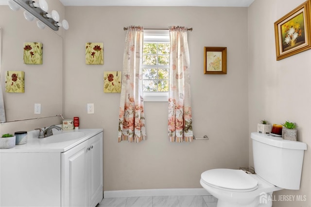 half bath with baseboards, vanity, toilet, and marble finish floor