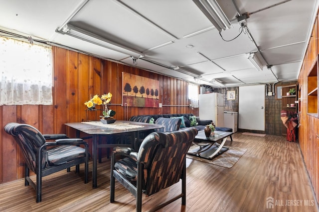 dining space with wooden walls, baseboards, and wood finished floors