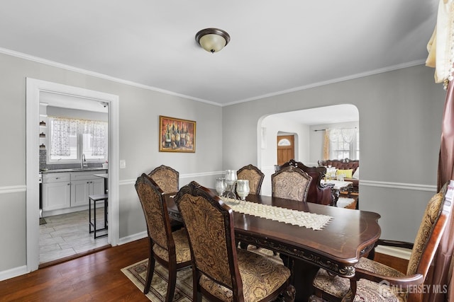 dining area featuring crown molding, arched walkways, and dark wood-style floors