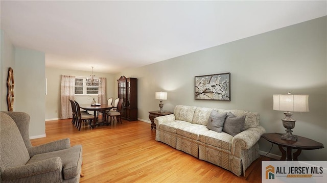 living area featuring baseboards, an inviting chandelier, and light wood-style flooring