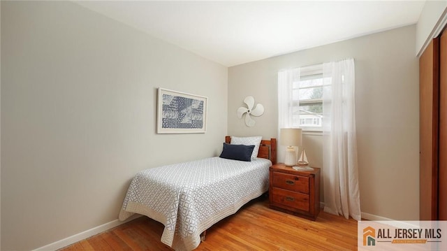 bedroom with light wood finished floors, baseboards, and a closet