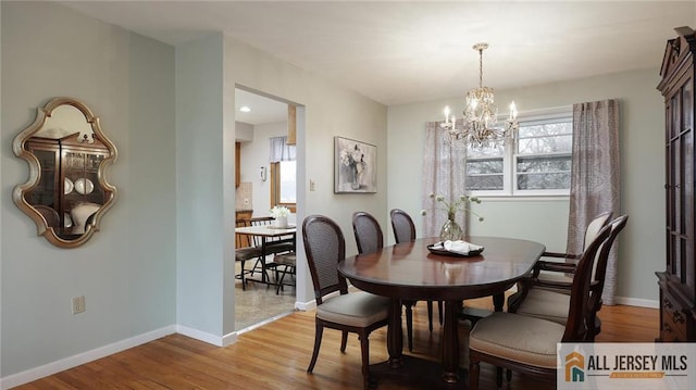 dining area featuring baseboards, a healthy amount of sunlight, a chandelier, and wood finished floors